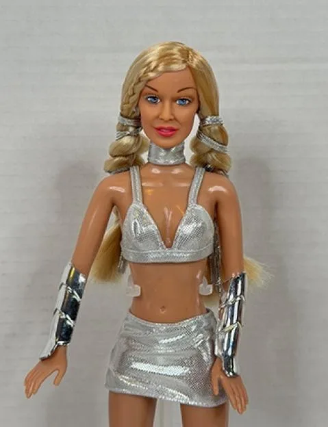 A Kylie Minogue fashion doll dressed in a silver two-piece outfit with matching arm guards.