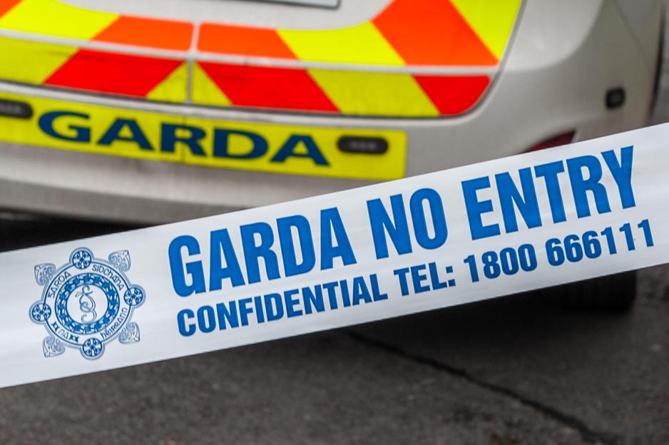 Garda "No Entry" tape stretched in front of an Irish police patrol car.