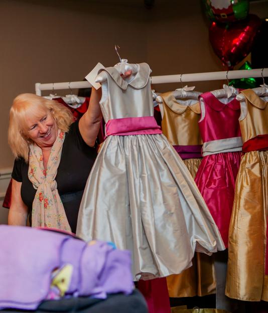 Jean O'Brien holding up a silver dress with a pink sash.