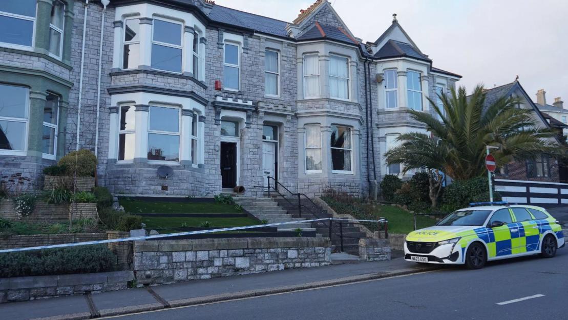 Police investigating an acid attack stand outside a property in Plymouth.