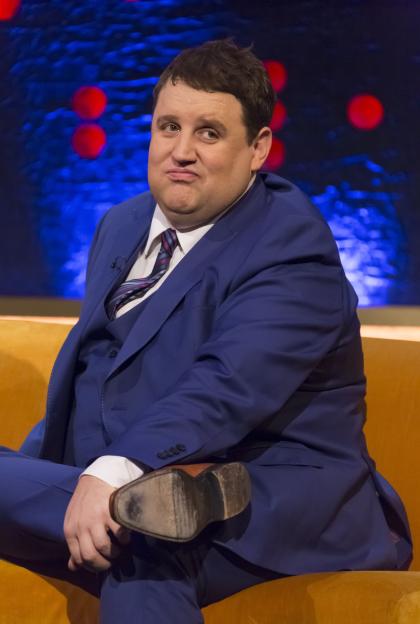 Comedian Peter Kay sitting on a yellow couch.