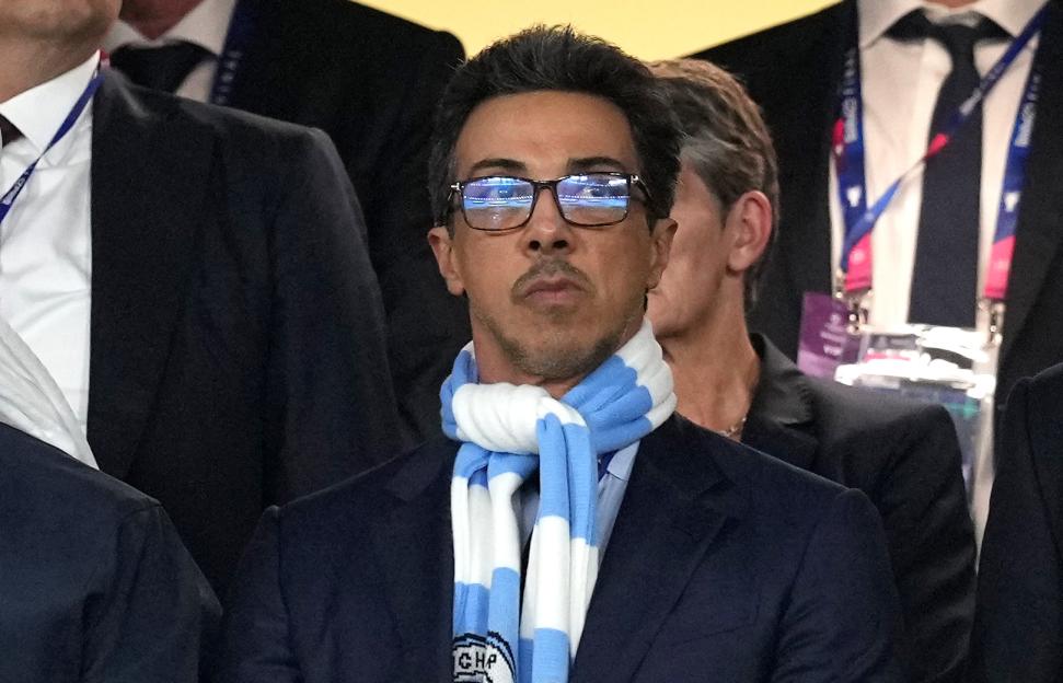 Manchester City owner Sheikh Mansour bin Zayed bin Sultan Al Nahyan wearing glasses and a light blue and white striped scarf.