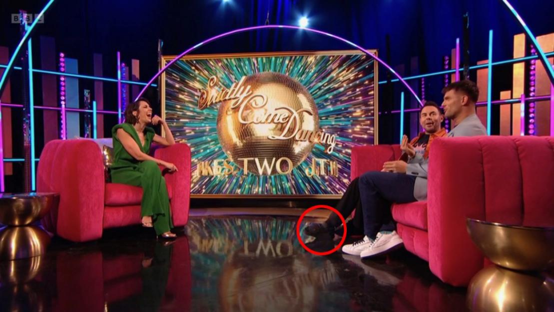 A female and two males sitting on hot pink couches on the set of Strictly Come Dancing.