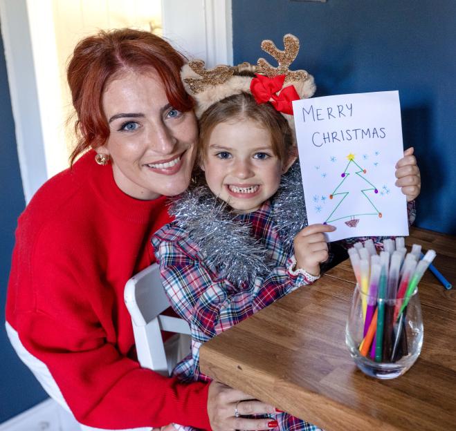 Little Poppy Catterall and her mother Che holding a Christmas card drawing.