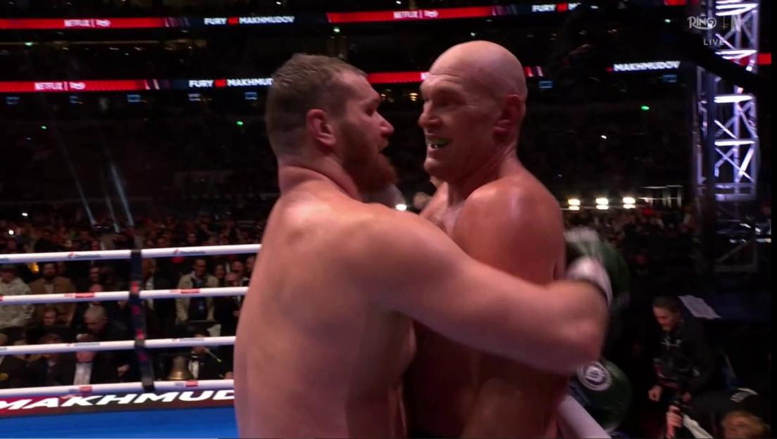 Two boxers embracing in the ring.