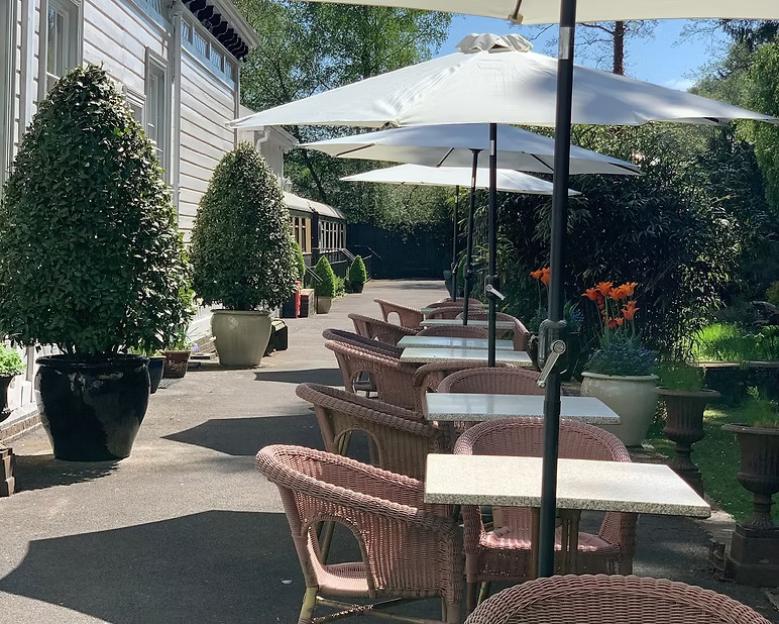 Outdoor seating area with wicker chairs and tables under white umbrellas.