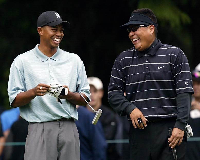 Three-time defending champion Tiger Woods (L) laug