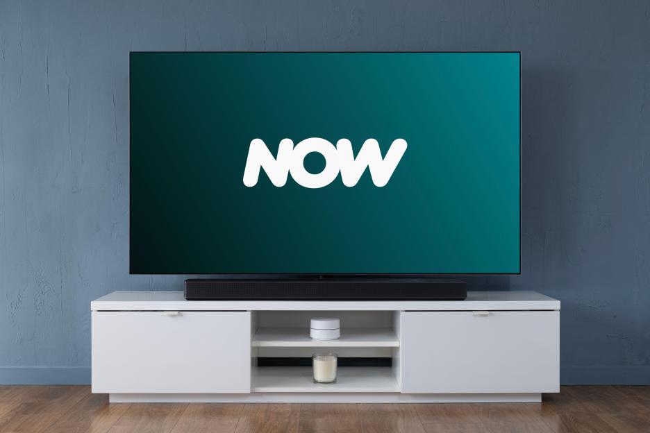 The NOW TV streaming service logo displayed on a widescreen OLED TV in a living room.