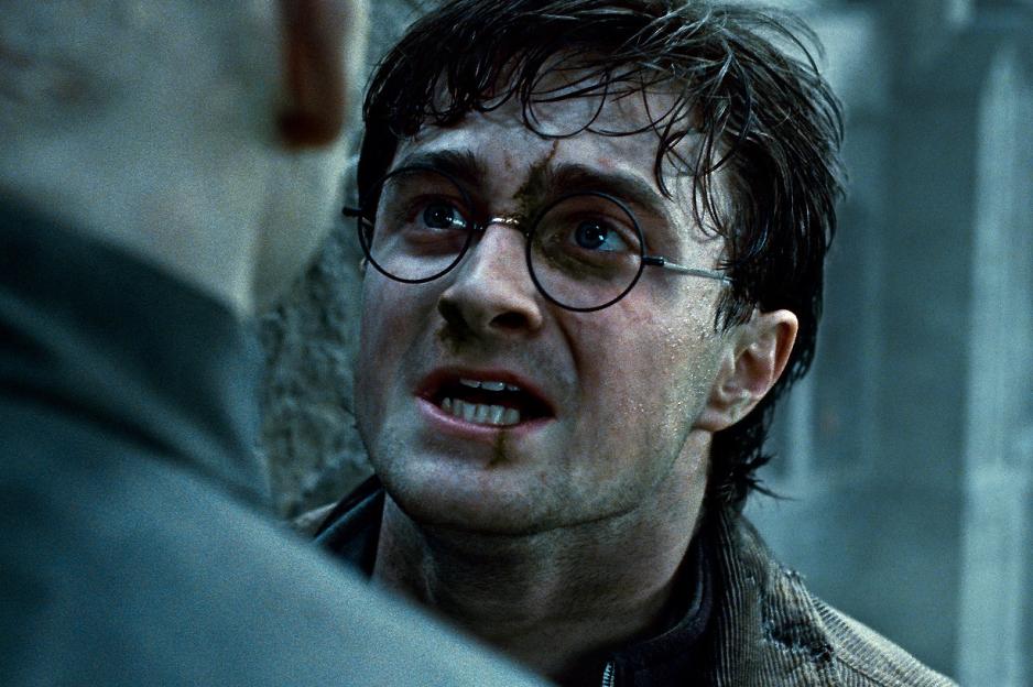 Daniel Radcliffe as Harry Potter, with a dirty face and open mouth, looking up at an unseen figure.