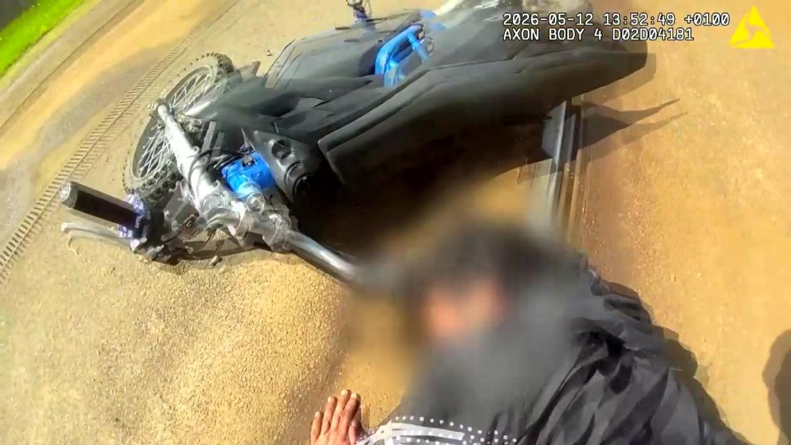 A police bodycam view of an e-bike flipped over on the ground with a person lying beside it.
