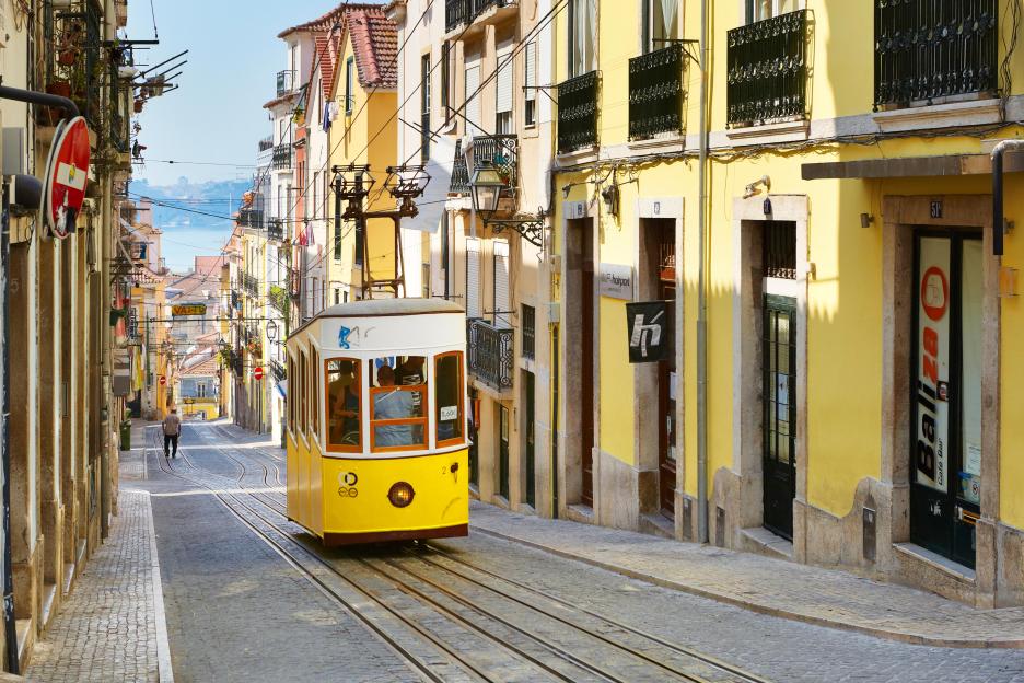 Yellow tram ascending a Lisbon street.