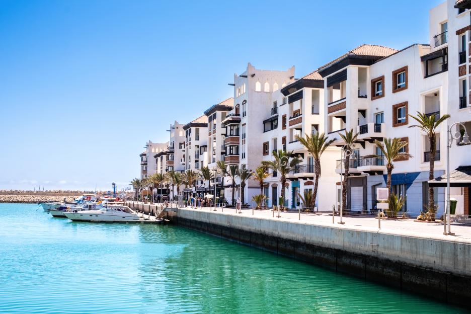 Agadir Marina, Morocco, with luxury apartments, moored boats, and shops lining the waterfront.