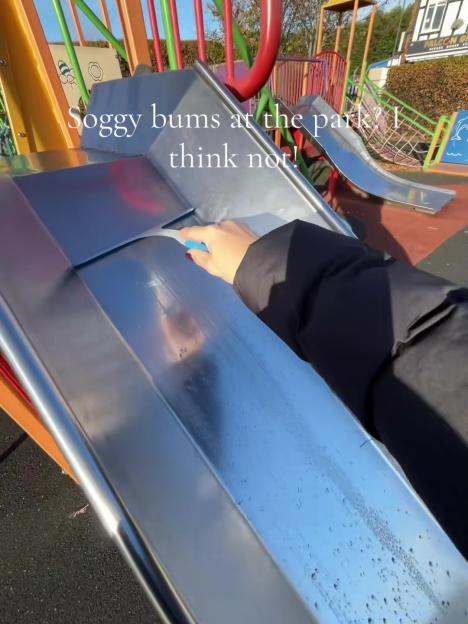 A person using a squeegee to dry water off a playground slide.