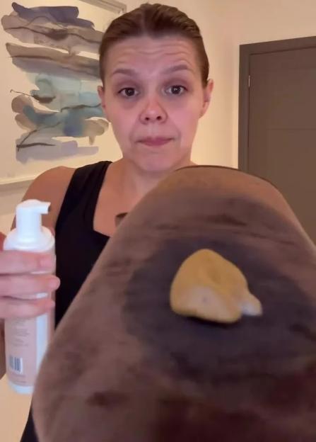 A woman holding a bottle of self-tanner and applying it to a tanning mitt.