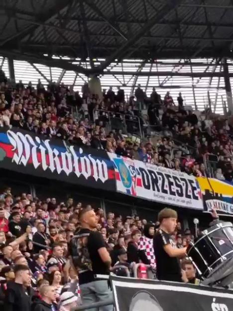 Crowd of football fans in a stadium with banners in the background.