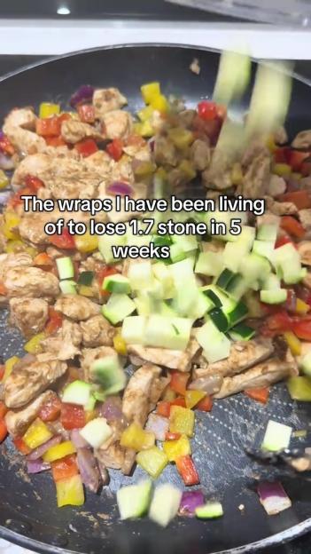 Chicken, bell peppers, and zucchini being cooked in a pan.