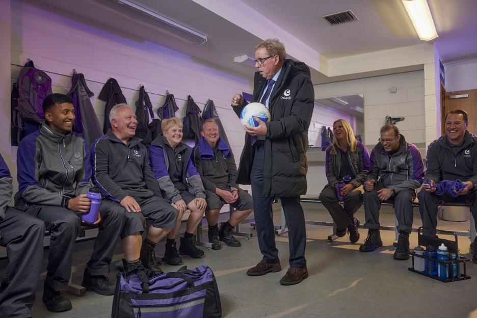 Harry Redknapp holding a football, talking to Ocado staff.