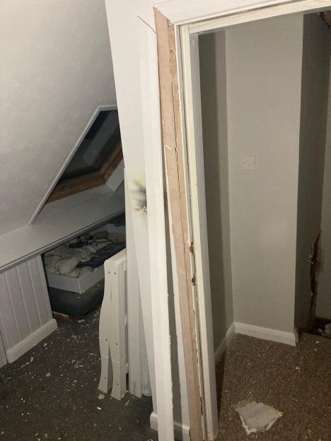 A bedroom damaged by lightning, with debris scattered across the carpet and a visible scorch mark on the wall.