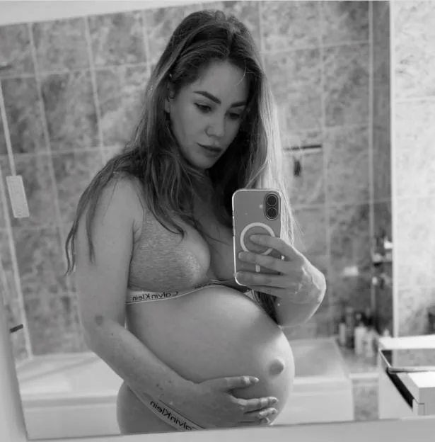 Black-and-white selfie of pregnant Roxanne McKee showing her baby bump in a bathroom mirror.