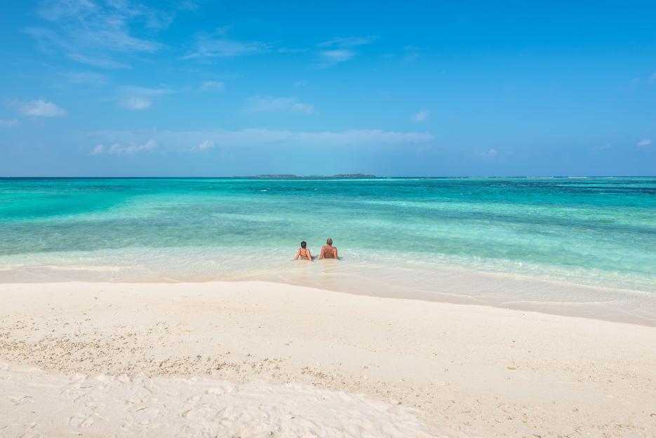 Couple enjoying the sun on a sandbank in the Maldives.