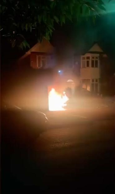 A large fire in front of a house at night.
