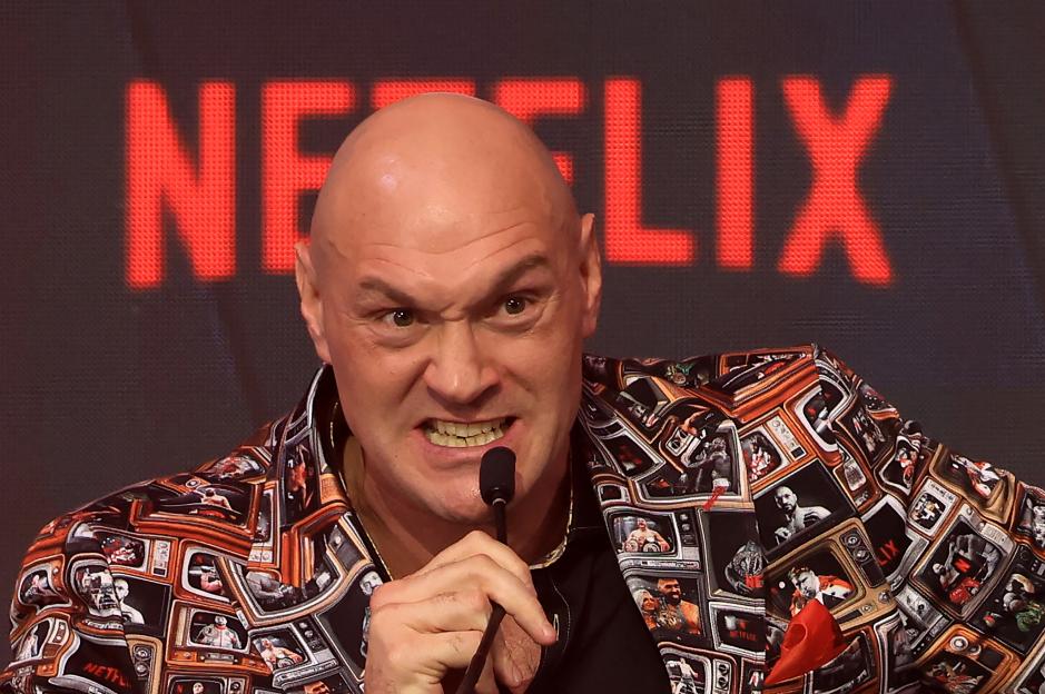Tyson Fury speaking into a microphone, grimacing, with a Netflix logo in the background.