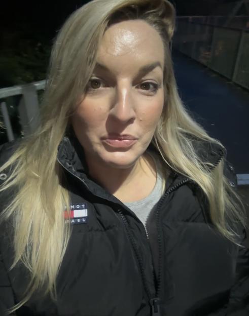 A woman with long blonde hair and a black Tommy Jeans puffer jacket.