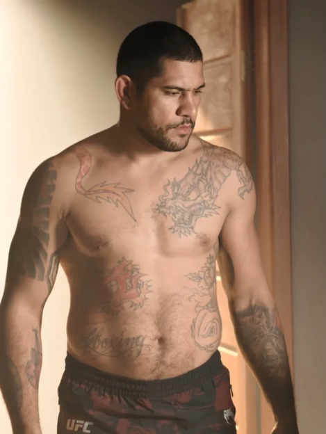 A shirtless man with numerous tattoos on his arms, chest, and stomach.