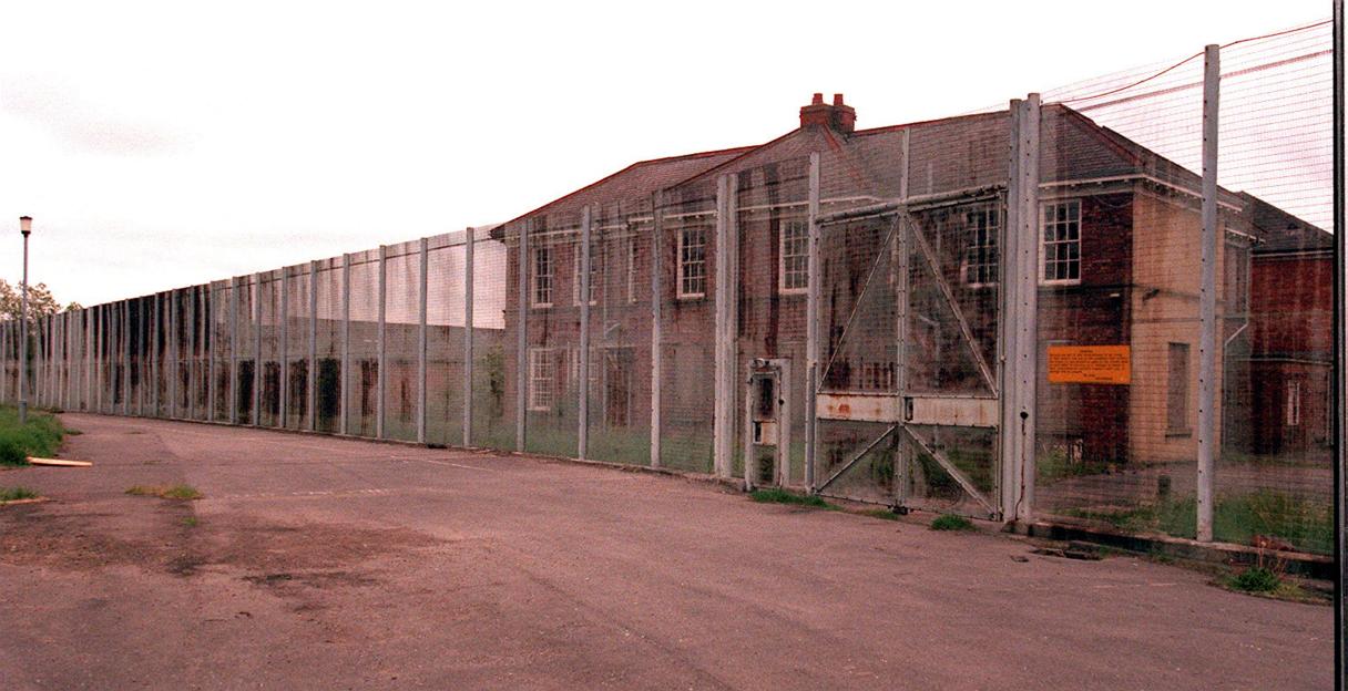 Derelict Medomsley Detention Centre near Consett, County Durham, with a long fence and closed gates.