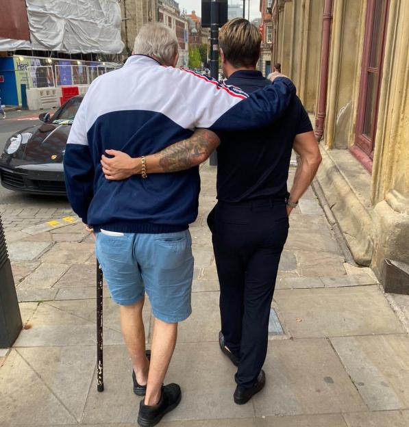 Tom Zanetti with his arm around his grandad, walking down a street.