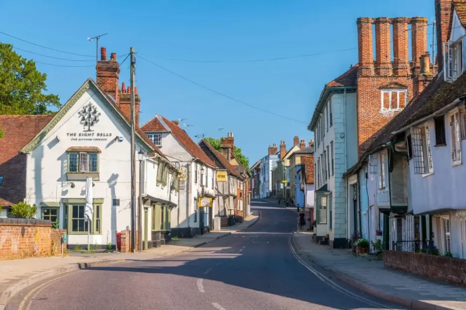 A street scene in Saffron Walden, Essex, England, showing historic buildings under a clear blue sky.
