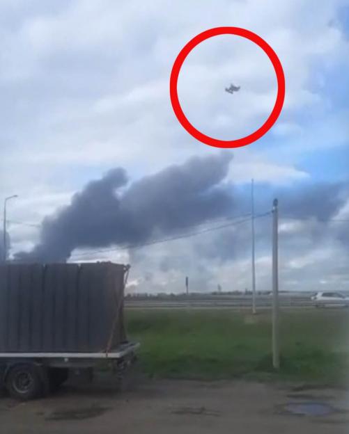 Smoke rising near a truck and a distant aircraft.