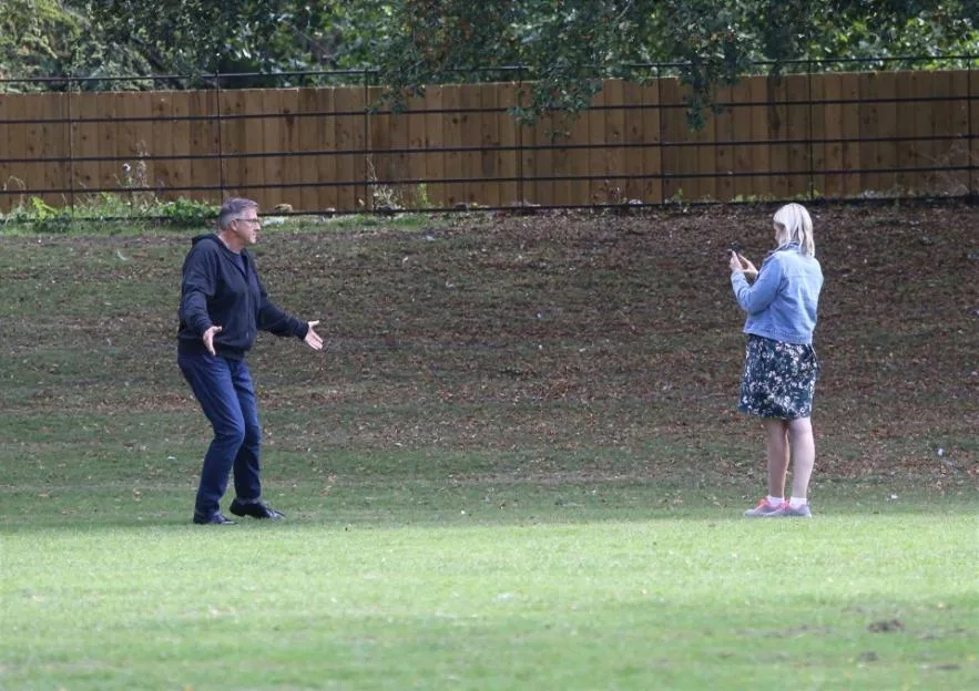 Graeme Hall, known as “The Dogfather,” films clips for social media with his girlfriend, Nicola Worth, in a park.