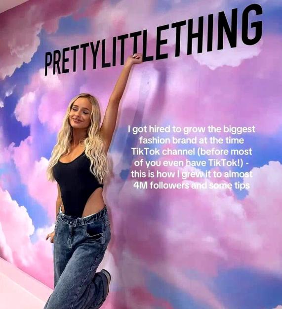 A woman posing in front of a cloud-painted wall with "PRETTYLITTLETHING" written on it.