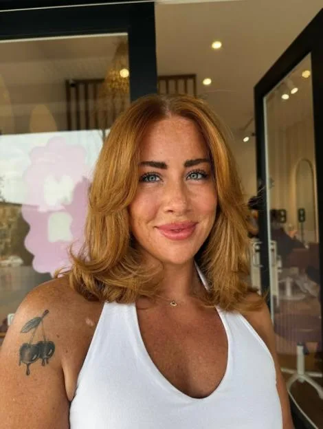 Polly Sellman with red hair and a cherry tattoo.