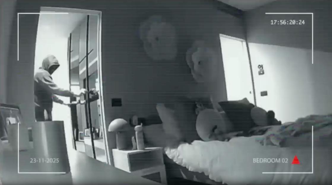 CCTV footage of a robber in a hooded sweatshirt entering a bedroom.