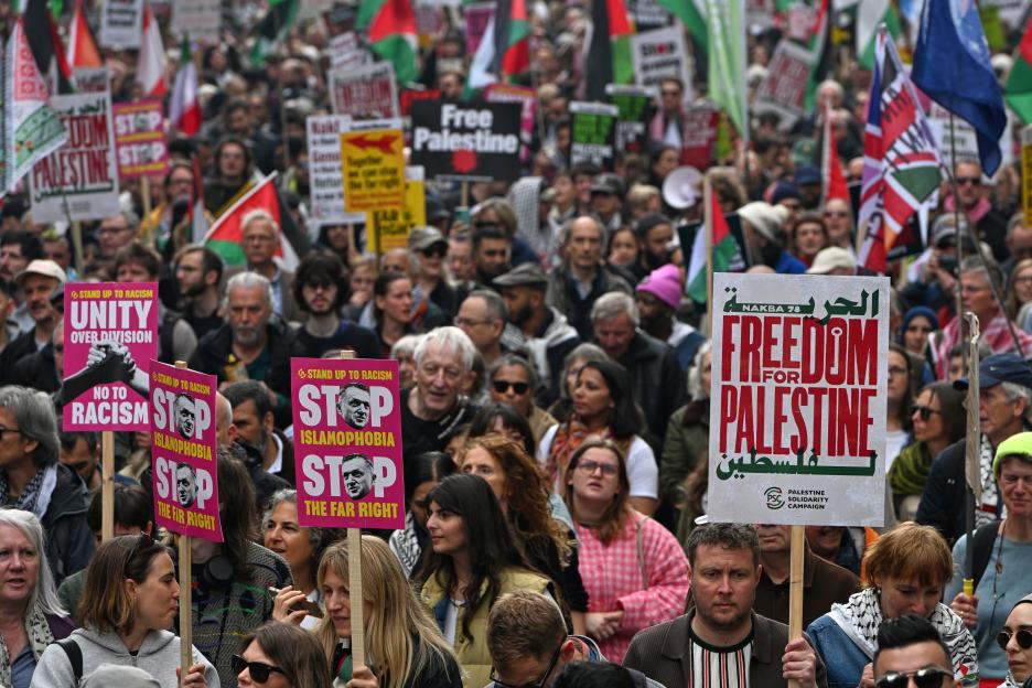 Protesters march in a pro-Palestine demonstration, holding signs that read "Free Palestine" and "Freedom for Palestine", as well as signs against racism, Islamophobia, and the far right.