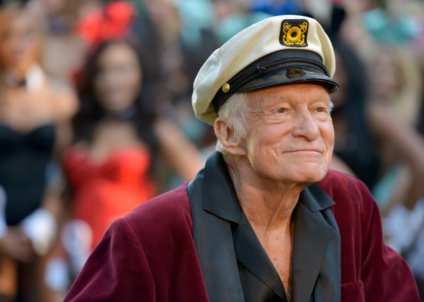 Hugh Hefner in a captain's hat and red velvet jacket.