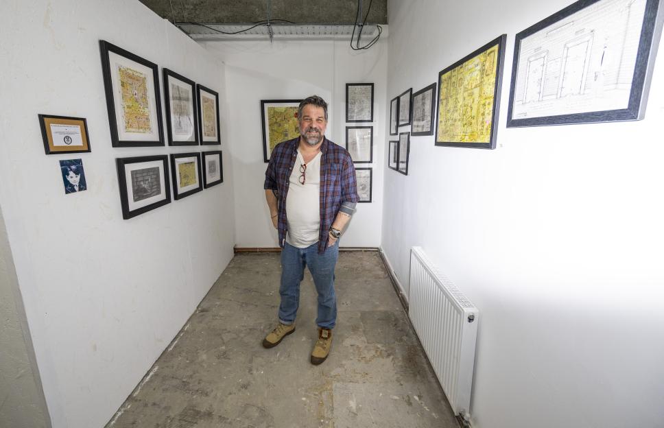 Gallery owner Nik Cornwell standing in a cell-sized corner of his gallery with artworks by Charles Bronson.