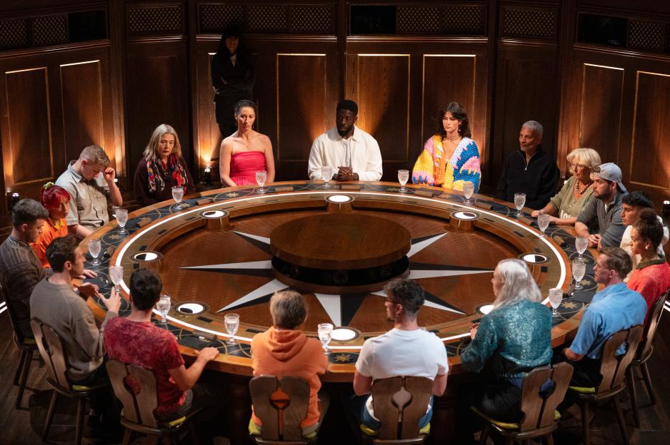 The Cast of The Traitors S4 seated at a round table with a large compass rose design on its surface.