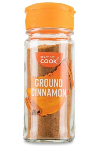 Glass jar of ground cinnamon with an orange lid.