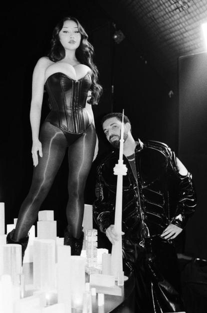 Louisa Khovanski standing in a corset and tights next to Drake, who holds a model of the CN Tower.