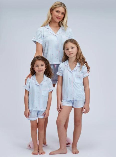 A woman and two young girls modeling matching light blue and white striped pajamas with pink hearts.
