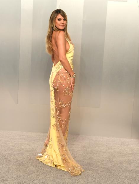 Heidi Klum posing on the red carpet in a sheer, embellished yellow gown.