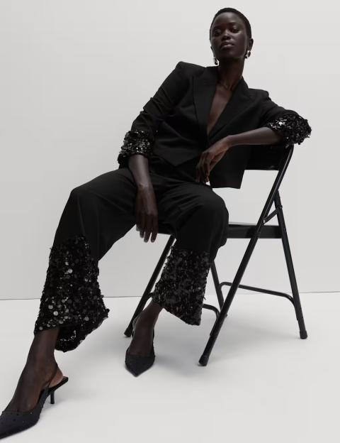 A model showcasing black sequin paneled straight-leg trousers along with a sequin detail top.