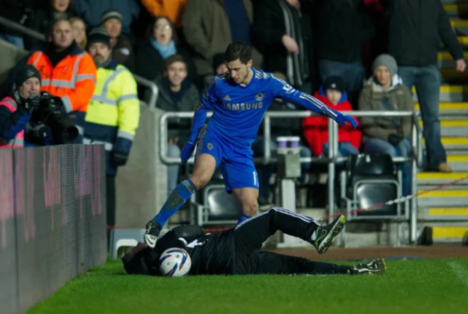Footballer Eden Hazard kicking a ball boy.