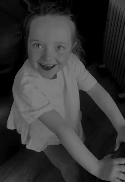 A young child with a wide smile and bright eyes looks up at the camera.