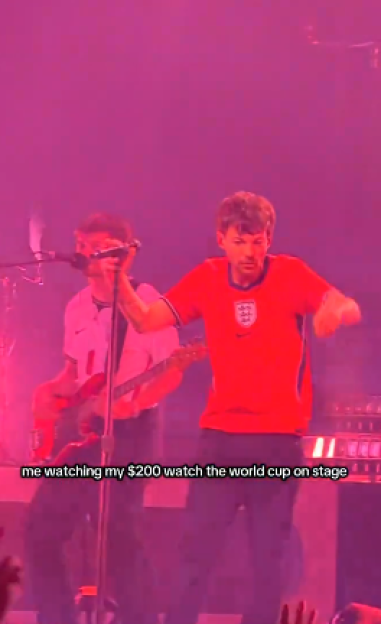 Louis Tomlinson performing on stage in a red England soccer jersey.