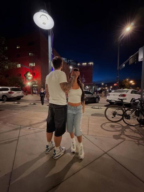 Sam Taylor and his new girlfriend pose on a city street at night.