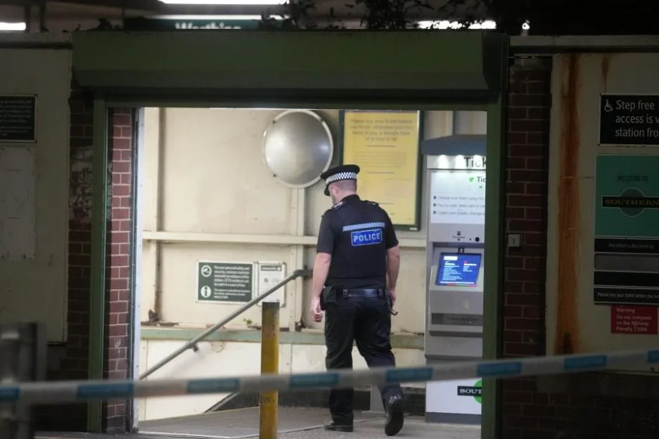 Police officer guarding the entrance of a closed Worthing railway station.